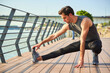 © Teodor Lazarev - Young adult man stretching legs and arms outdoors next to a river, preparing for a running workout in an urban park, focusing on physical health and exercise