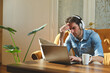 © Teodor Lazarev - Young man experiencing headache and stress while working on laptop, concentrating intensely and dealing with fatigue or a problem remotely from home