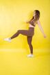© KONSTANTIN SHISHKIN - Woman exercising brown sportswear doing a high kick