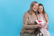 © New Africa - Little girl greeting her grandmother with holiday card and gift on light blue background, space for text