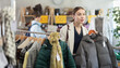 © JackF - Selective young female customer holding a hanger with puffer jacket in clothing-store on Black Friday