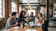 © Matt - Four coworkers discussing charts and laptops in brick office