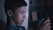 © vla - Teenage Boy Using Smartphone in Low Light Interior, the boy is having a good time