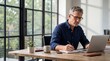 © HikikomorAI - Middle-aged man working on laptop at rustic desk in modern office