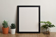 © Mulad Images - Photo frame mockup with small potted plant on table.