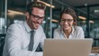 © Dao - Two business people using a laptop together while sitting in a meeting. Happy business people looking at a slide presentation in an office.