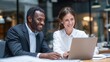 © Dao - Two business people using a laptop together while sitting in a meeting. Happy business people looking at a slide presentation in an office.