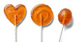 © Trieu - three orange hard candy lollipops, including a heart shape, a swirl, and an oval, displayed against a transparent background.