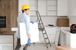 © Pixel-Shot - Male worker with shelf assembling furniture in kitchen, back view