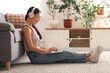 © Pixel-Shot - Beautiful young happy Asian woman in headphones with laptop listening music on floor at home