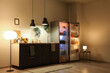 © Pixel-Shot - Open fridge full of different fresh products with lamps and utensils on counter near beige wall in kitchen at night