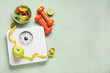 © Pixel-Shot - Weight scales with measuring tape, dumbbells and healthy food on grunge green background. Slimming concept
