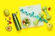 © Pixel-Shot - Weight scales with measuring tape, dumbbells, bottle of water and healthy food on yellow background. Slimming concept
