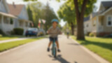 Blurred background of small child learning to ride a bicycle during World Bicycle Day celebration, a smiling kid with a colorful bicycle with training wheels and a small helmet, a quiet suburban.