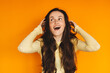© zvkate - Shocked young woman holding head in hands with open mouth on orange background, surprised girl looking away in disbelief, amazing news or problem concept, emotional studio portrait