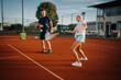 © Ljustina - Tennis coach teaching young girl forehand on clay court