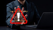 © Concept Style - Cybersecurity threat prevention and digital risk warning concept. Businessman showing a stop hand gesture to a glowing red alert triangle, broken links, and malware skull holograms.