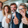© Kowit - Four diverse professionals smiling and giving thumbs up, conveying positivity and teamwork in a bright office setting.