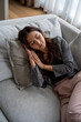 © Parichat - Young asian woman sleeping peacefully on a comfortable couch, taking a break indoors