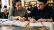 © The Origin 33 - Young man and woman student sit at library table to study college book with intense focus. Concentrated classmate write in notebook while female point at text to learn academic subject