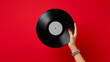 © INSPIRIA.K - Woman holding vintage vinyl record against red background. Music lover with retro disc for turntable. Analog audio hobby, sound entertainment and listening collection concept for vinyl disc.
