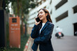 © Parichat - Smiling young Asian businesswoman talking on smartphone in city