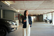 © Parichat - Young Asian woman walking through underground parking lot holding smartphone