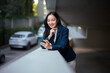 © Parichat - Young Asian business woman smiling checking smartphone