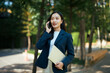 © Parichat - Young asian businesswoman talking on cell phone outdoors