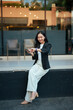 © Parichat - Young Asian woman interacting with smart devices outdoors