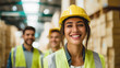 © rohit - Confident Female Warehouse Worker in Hard Hat and Safety Vest Smiles at Camera, Colleagues in Background, Industrial Environment