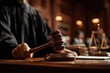 © Olena - Partial view of a blurred judge in a courtroom holding a wooden gavel