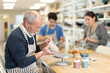 © JackF - Mature man at table molds cup from wet clay in a pottery workshop