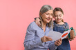 © New Africa - Little girl greeting her grandmother with holiday card and gift on pink background, space for text