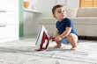 © New Africa - Child safety at home. Little boy playing with iron indoors, space for text