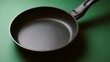 © sornram - A high-quality, non-stick frying pan on a green background, perfect for cooking delicious meals with ease.