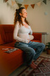 © wifesun - Pregnant woman meditating for relaxation and mindfulness, cradling her baby bump while practicing calm breathing exercises at home, surrounded by pregnancy test and ultrasound scans