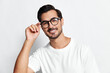© SHOTPRIME STUDIO - Smiling man wearing glasses and a white t-shirt, looking at the camera while adjusting his glasses with a cheerful expression against a plain white background.