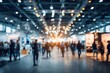 © Wahid - Blurry wide shot of a busy exhibition hall with many people and bright lights