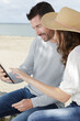 © auremar - couple using a tablet by the seaside