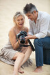 © auremar - mature couple on sand dune checking camera screen