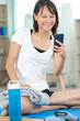 © auremar - pretty young woman sitting on exercise mat with mobile phone