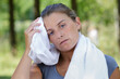 © auremar - woman wiping perspiration with towel after exercising outdoors