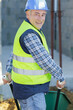 © auremar - builder in workwear and helmet carries an empty wheelbarrow