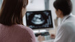 © Ally_art - Woman patient looking at ultrasound screen with doctor. Pregnant female checking stomach health during medical consultation. Diagnostic imagery for prenatal care and obstetric medicine.
