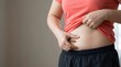 © Yassine - Woman holding and pinching her excess belly fat with both hands, focusing on weight concerns.
