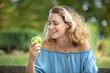 © auremar - happy smiling young woman eating organic apple at her garden