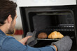 © auremar - man tending croissants in the oven at home