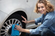 © auremar - smiling woman use sponge to wipe black tire