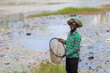 © arrowsmith2 - Happy African Man Holding Round Fishing Net by Lotus Pond